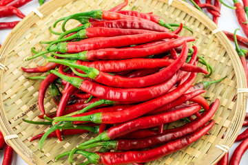 Bamboo sieve filled with fresh red peppers on white background