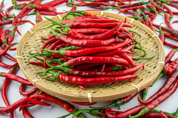Bamboo sieve filled with fresh red peppers on white background