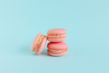Tasty french pink macarons on a blue pastel background.