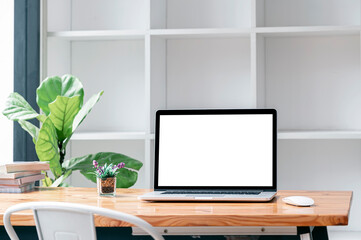 Blank screen laptop computer on wooden table in living room.