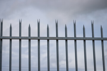Iron fence behind the house with cloudy atmosphere