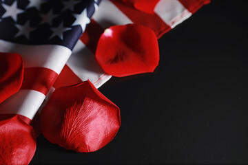 American flag and rose flower on the table. Symbol of the United States of America and red petals....