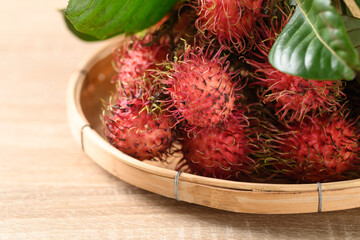 Ripe rambutan fruit in a bamboo basket on wooden background, Rambutan is tropical fruit and native Southeast Asia, juicy and sweet taste