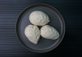 steamed fresh vegetables bun white baozi in leaf shape on dark grey wood background dim sum halal menu