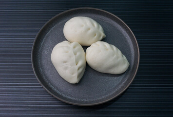 steamed fresh vegetables bun white baozi in leaf shape on dark grey wood background dim sum halal menu