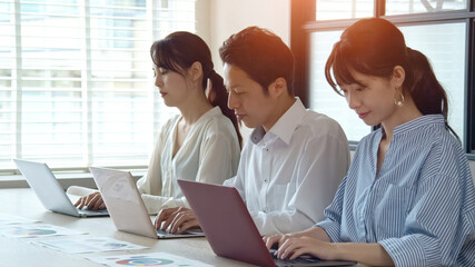 並んでPC作業する人々　ビジネスとチームワーク