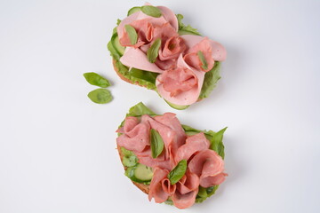 Open ham Sandwich with cucumbers, basil, and a crusty slice of rye bread and salami