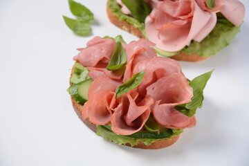 Open ham Sandwich with cucumbers, basil, and a crusty slice of rye bread and salami