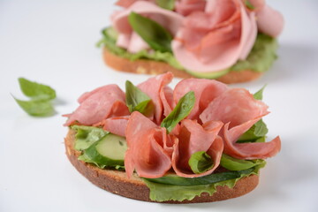 Open ham Sandwich with cucumbers, basil, and a crusty slice of rye bread and salami