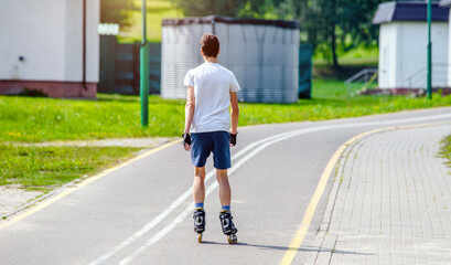 A guy and on roller skates rides in the Park
