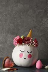 Сute pumpkin with halloween makeup against gray textured background