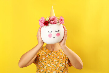 Girl holds pumpkin with halloween makeup on yellow background
