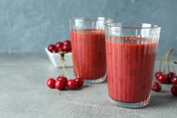Glasses of cherry smoothie and ingredients on gray textured table