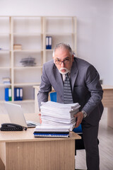 Old male employee working at workplace