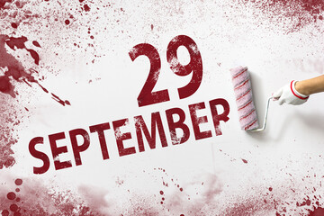 September 29th. Day 29 of month, Calendar date. The hand holds a roller with red paint and writes a...