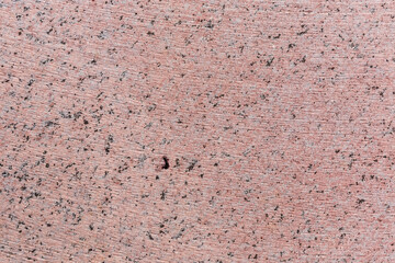 Flat pink granite block side with stone cutting tool traces