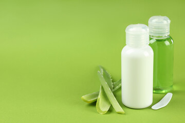 Aloe vera cosmetics and leaves on green background