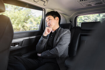 business man thinking while sitting in the back seat of car