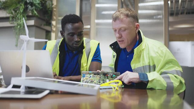 Engineer and workman maintenance of alternative energy at the modern office,solar panels,controller box and wind turbine model.green renewable energy and sustainability development concept.