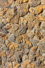 The rough masonry of the wall is lined with old orange shell rock. Vertical image.
