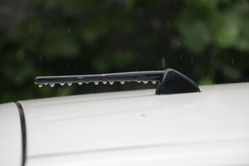 Close up picture of a car's antenna, on a rainy day.