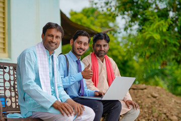 Young indian banker or agronomist showing some detail to farmers in laptop at home