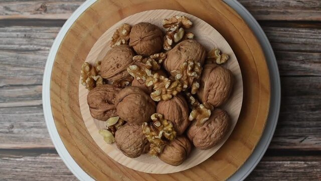 Plato de madera girando con nueces peladas y con c&aacute;scara