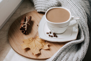 cup of coffee with coffee beans and cinnamon sticks on a wooden tray