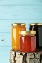 Assortment of jams, seasonal fresh berries and fruits on blue background.