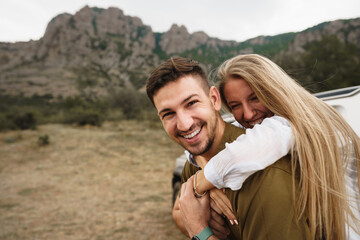Happy loving couple hiking and hugging in mountains