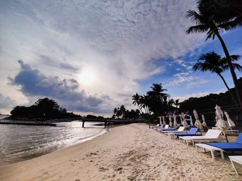 The dramatic cloud formation on a clear sunny day over the rows of sunbed on the sandy beach of Sentosa Island, Singapore