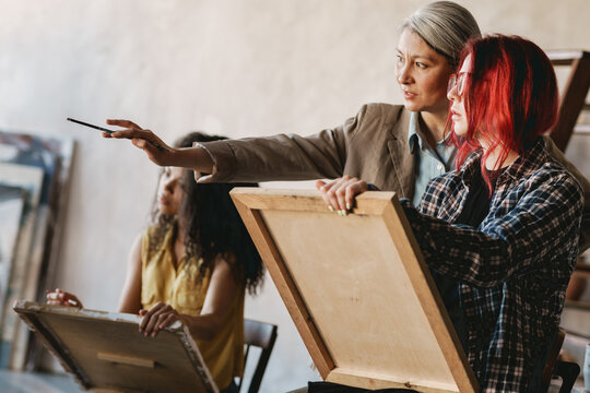 Mature teacher talking with her student during class in art school