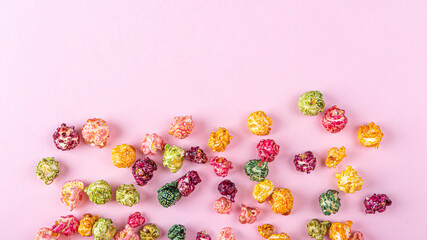 Colorful rainbow caramel candy popcorn on pink background. Cinema snack concept. Watching movie and entertainment background. Copy space for text, flat l