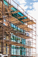 Scaffolding and scaffolding with wooden decks, against a blue sky. Performing construction work at height. Construction safety.