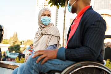Obraz na płótnie Canvas Muslim woman and disabled man wearing face mask talking to each other