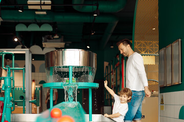 Father helps his son to play on water equipment in entertainment center. Tactile sensations. Children's emotions and joy . Working with children. learning through game.