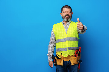 Portrait of senior construction worker in yellow vest in studio