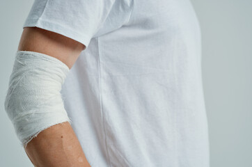 male patient in a white T-shirt with a bandaged hand isolated background