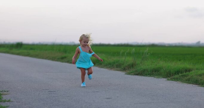 Ni&ntilde;a de dos a&ntilde;os corriendo en verano por un camino rural al atardecer