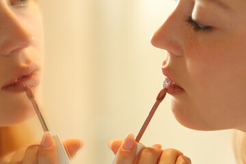 Woman painting lips looking at mirror