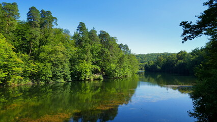 Fototapeta premium malerischer Bärensee bei Stuttgart umgeben von Laubwald und Kiefern, die sich im Wasser spiegeln