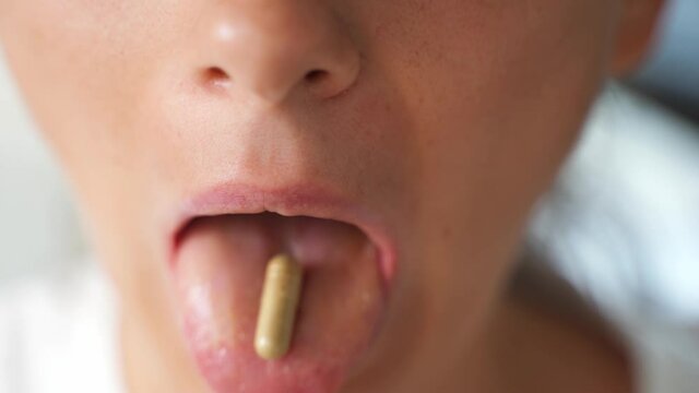Close up shot of woman mouth with vitamin capsule. Micro dosing for depression treatment. Vitamins and supplements preventive medicine
