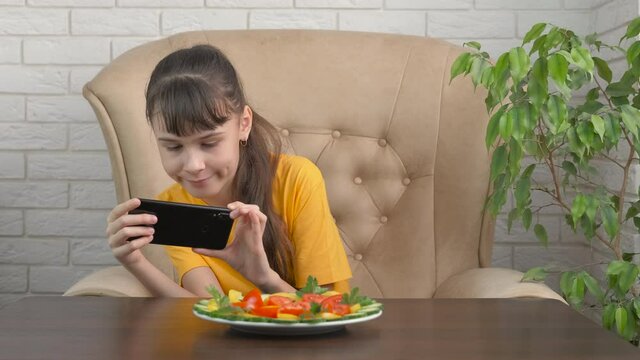 Take pictures of food. Teenager girl photographs salad with smartphone.