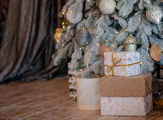 Beautiful Christmas gift boxes on the floor near the Christmas tree bokeh lights in the room. Christmas background with copy space and place for text. Christmas discount time