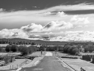 Black and white view down a road crossing a train line in rural Tasmania, Australia