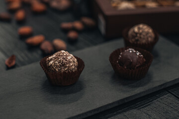 Handmade Chocolate raw candies on dark wooden rustic background with cacao beans. Dark milk chocolates set