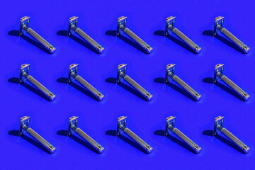 A pattern of dangerous razors. Shaving tool on a blue background with hard shadows.