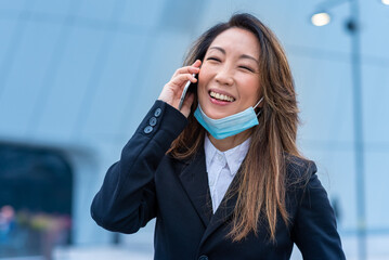 japanese business woman calling, confident and smiling entrepreneur wearing facemask, telecommuting...