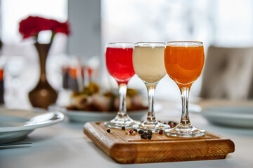 Shot of colorful alcoholic drink on a wooden stand against the background of a served table. Close-up, selective focus