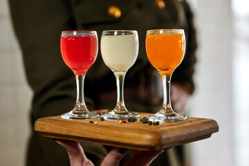 The waiter holds a set of multicolored alcohol shots. Close-up, selective focus